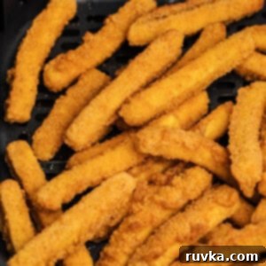 Cooked chicken fries in air fryer basket, showing their crispy texture.