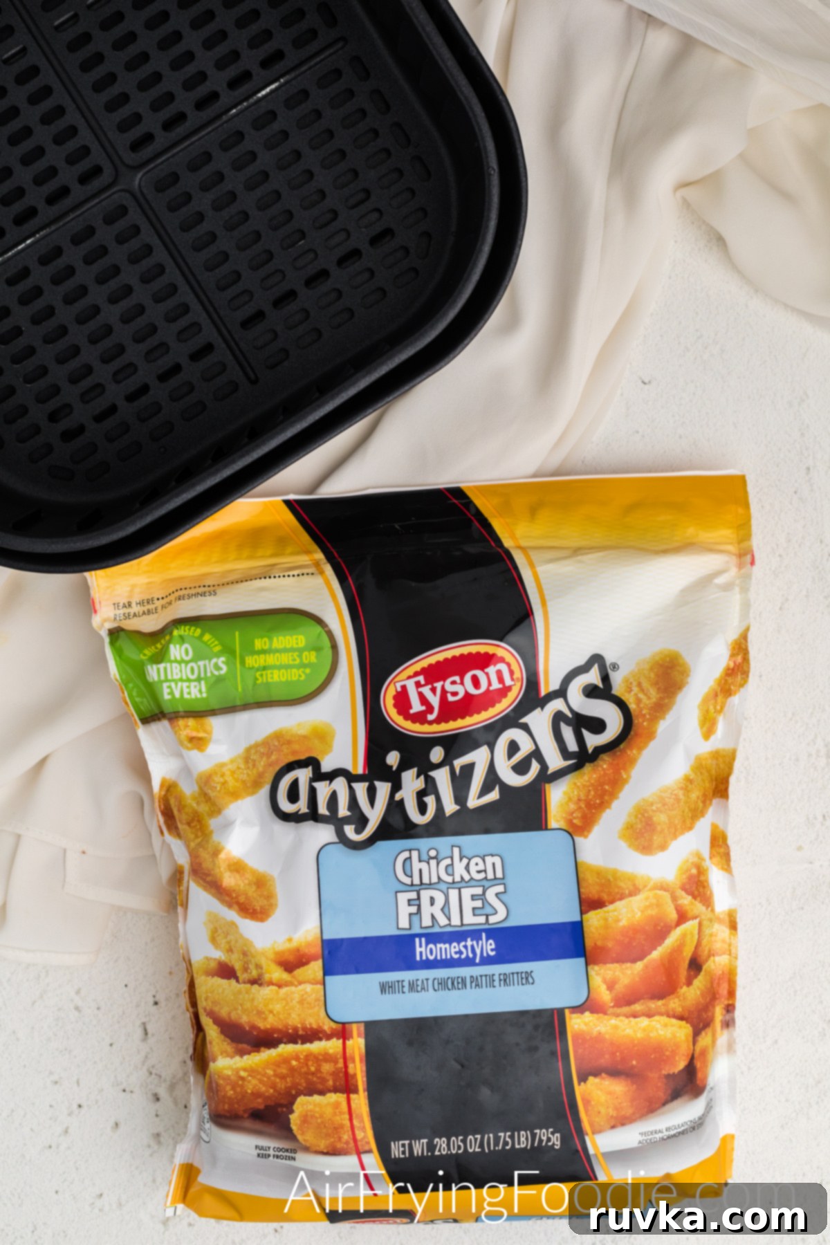 Tyson Frozen Chicken Fries in their packaging next to an air fryer basket, ready to be cooked.