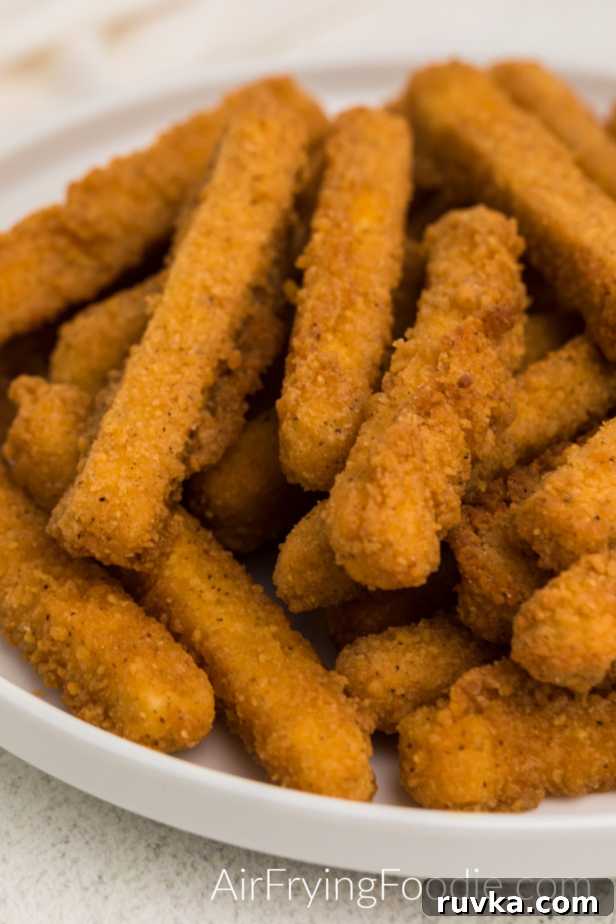 Air Fried Chicken fries arranged on a white plate, garnished with fresh parsley and ready to eat with dipping sauces.