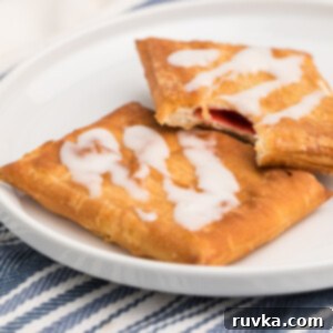 Flaky Air Fryer Strudel Bliss 8 Toaster strudel made in the air fryer on a white plate with a missing bite.