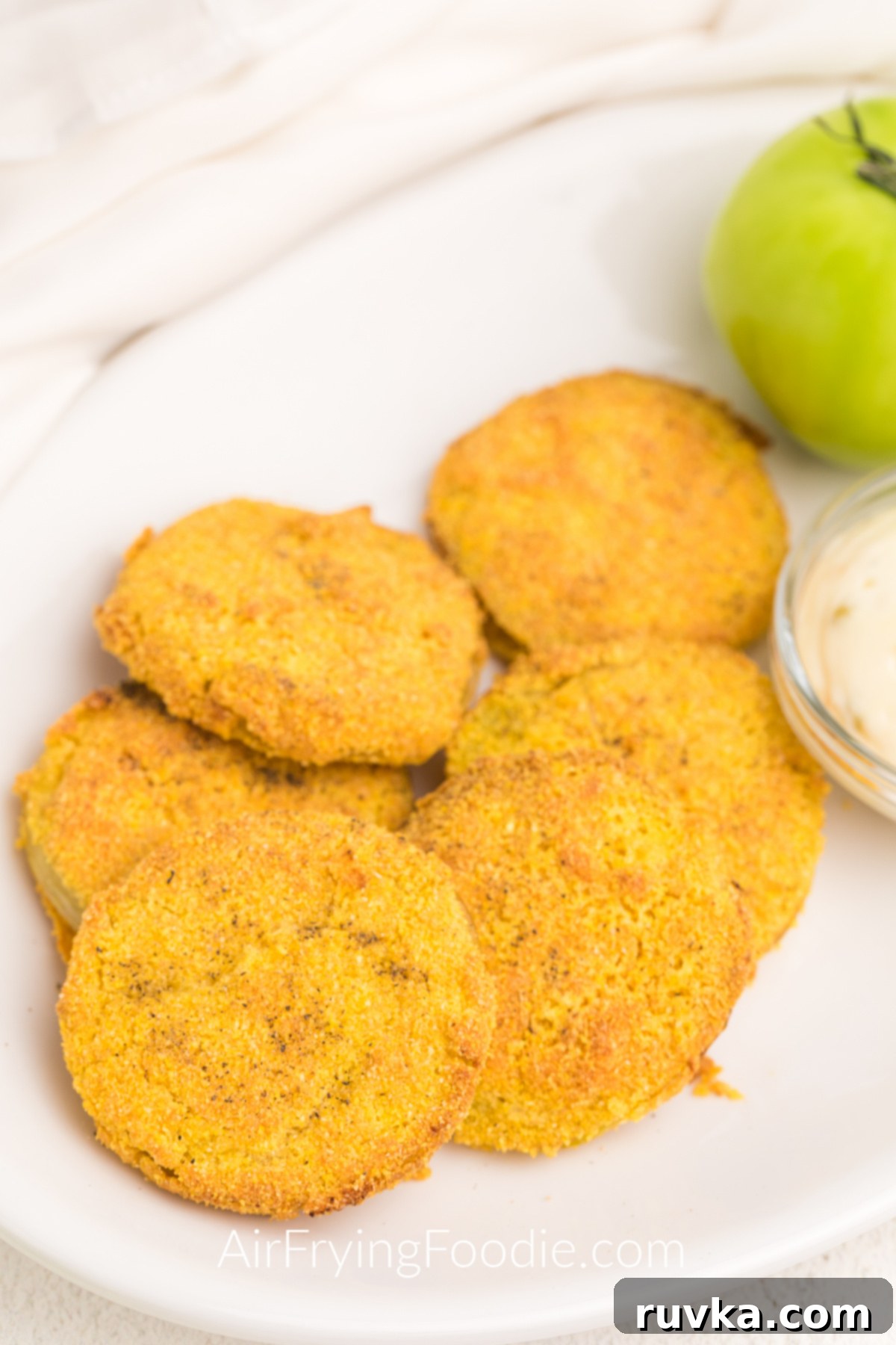 Crispy Air Fryer Fried Green Tomatoes 2 Air Fried Green Tomatoes on a white plate served with dipping sauce on the side.