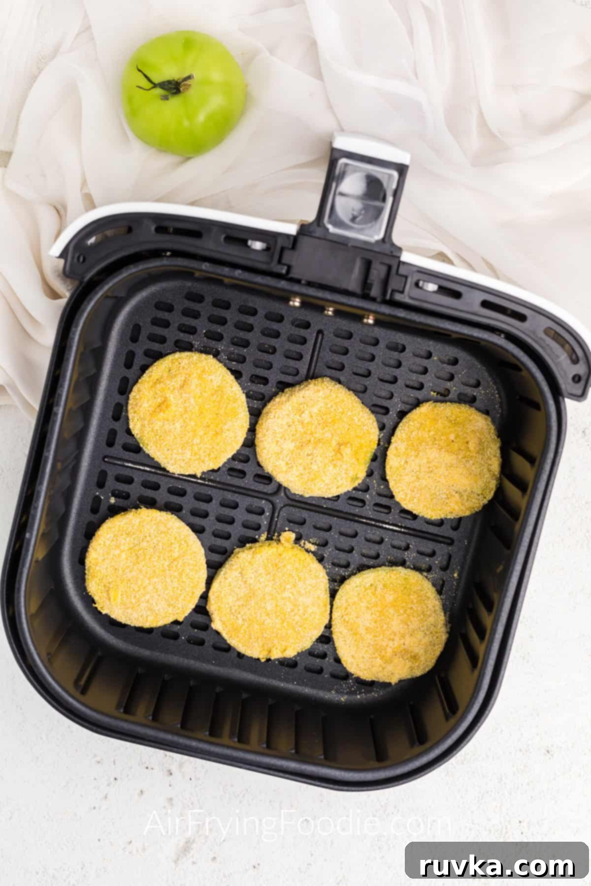 Crispy Air Fryer Fried Green Tomatoes 7 Coated green tomatoes in air fryer basket ready to be cooked.