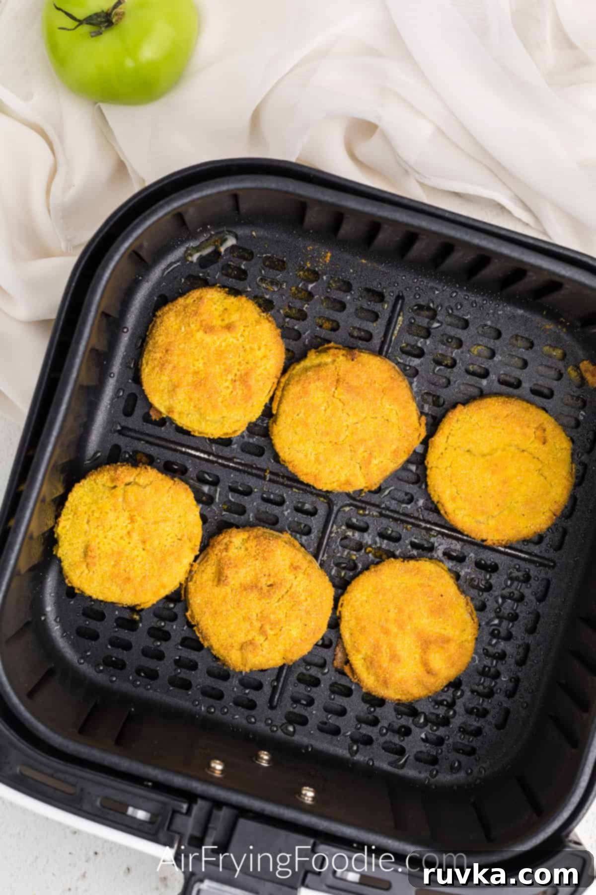 Crispy Air Fryer Fried Green Tomatoes 8 Air Fryer Fried Green Tomatoes in the basket of the air fryer, fully cooked and golden brown.
