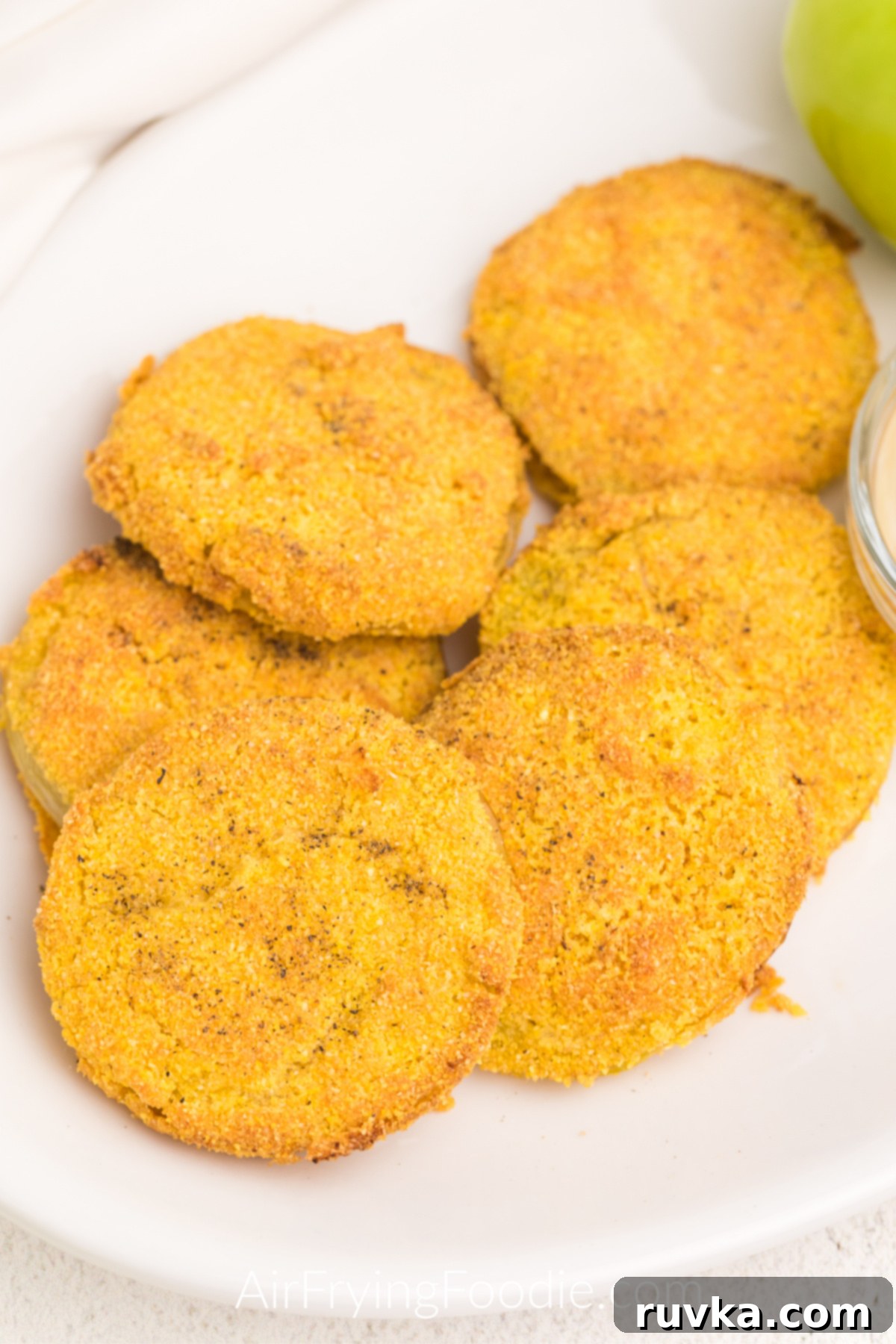 Crispy Air Fryer Fried Green Tomatoes 9 Close up photo of air fryer fried green tomatoes on a white plate with dipping sauce, ready to be served.