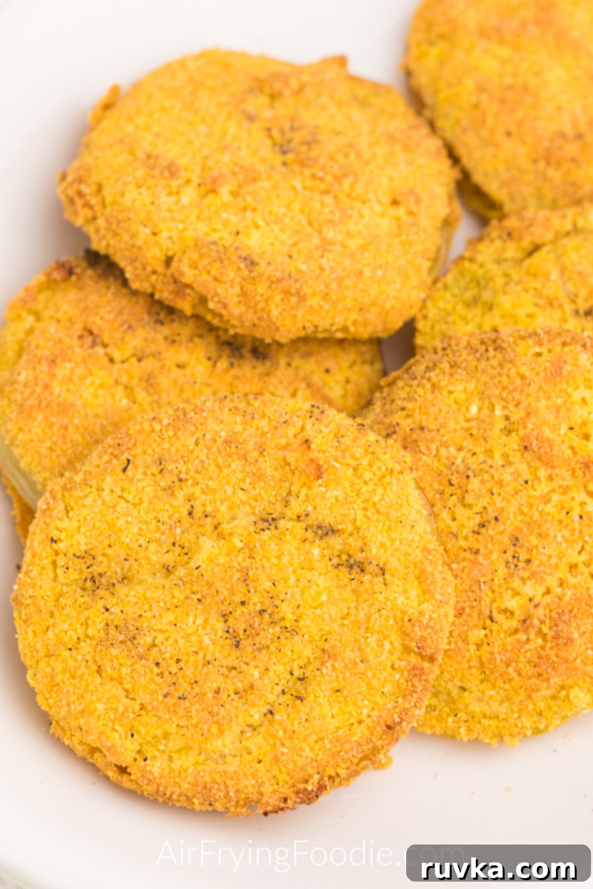 Crispy Air Fryer Fried Green Tomatoes 10 Close up of fried green tomatoes made in the air fryer and served on a white plate, ready to eat.