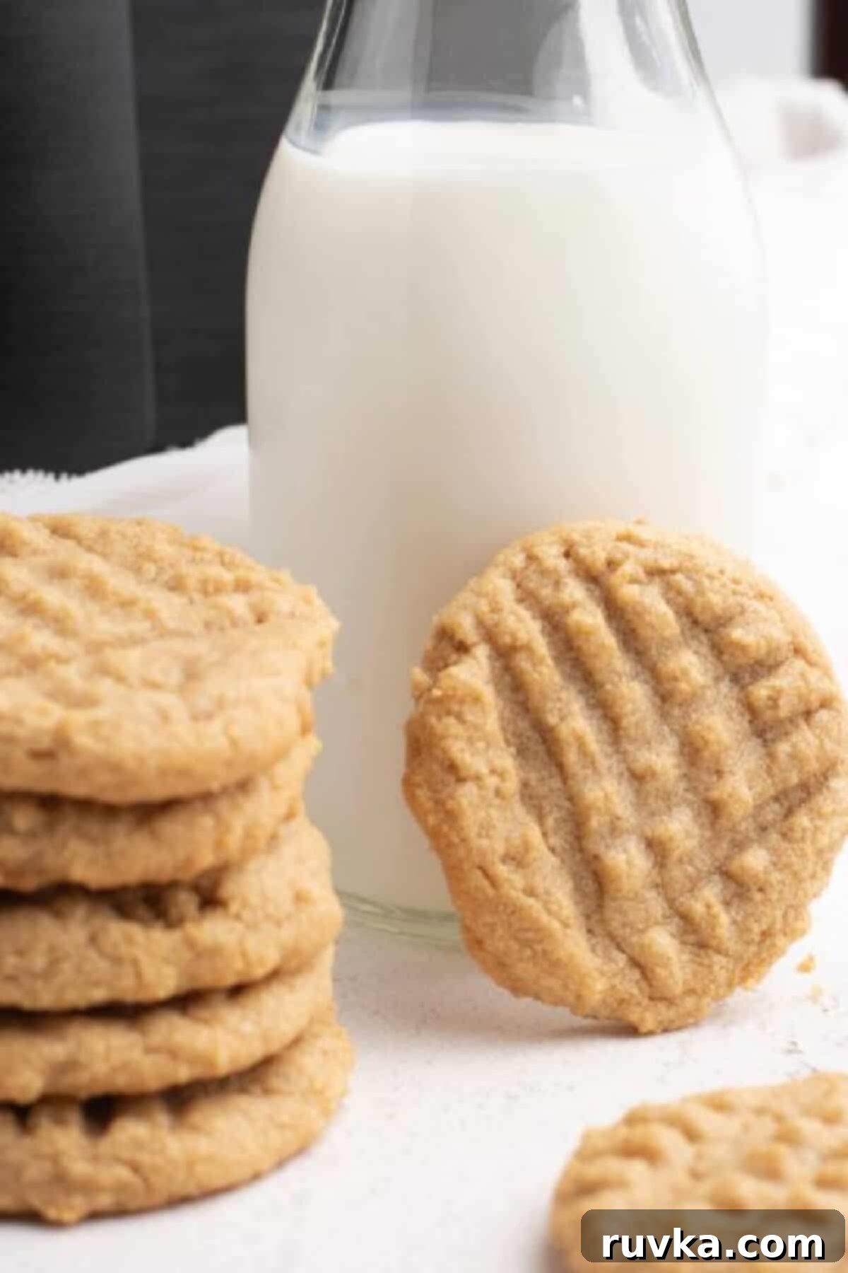 Chewy Air Fryer Peanut Butter Cookies 2 Close up photo of peanut butter cookies made in the air fryer, propped up on a glass of milk.
