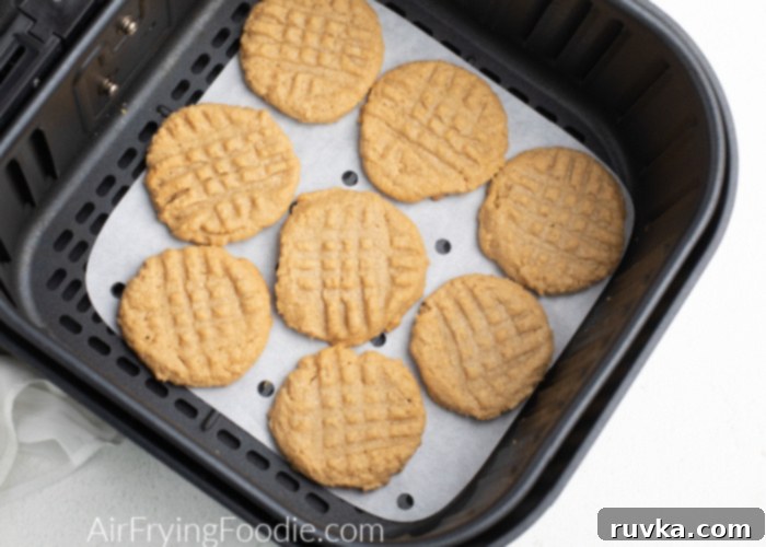 Chewy Air Fryer Peanut Butter Cookies 3 Peanut Butter cookies on a piece of parchment paper in the Air Fryer basket.