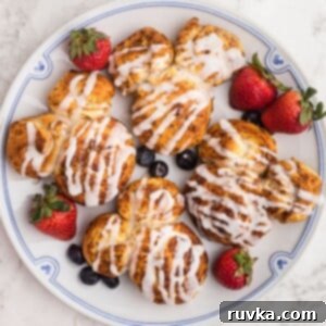 Easy Air Fryer Breakfasts 15 Adorable Mickey Mouse-shaped cinnamon rolls on a white plate, garnished with fresh berries on a marble table.