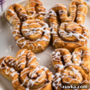 Easy Air Fryer Breakfasts 16 Air fryer cinnamon roll bunnies, glazed and ready to serve on a white plate, perfect for a festive breakfast.