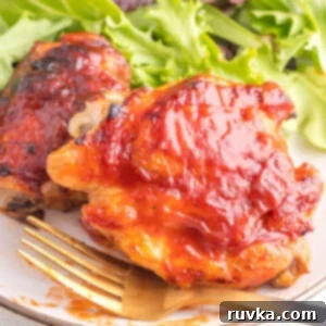 Perfect Air Fryer BBQ Chicken Thighs 6 BBQ chicken thighs made in the air fryer on a plate with a fork and a salad.