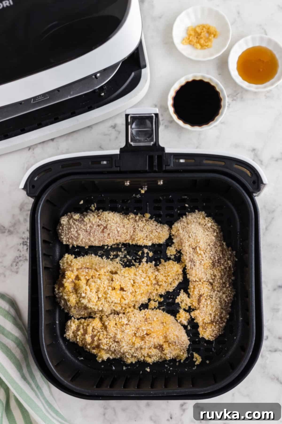 Crispy Air Fried Honey Garlic Chicken Strips 7 Breaded chicken tenders arranged in a single layer inside an air fryer basket.