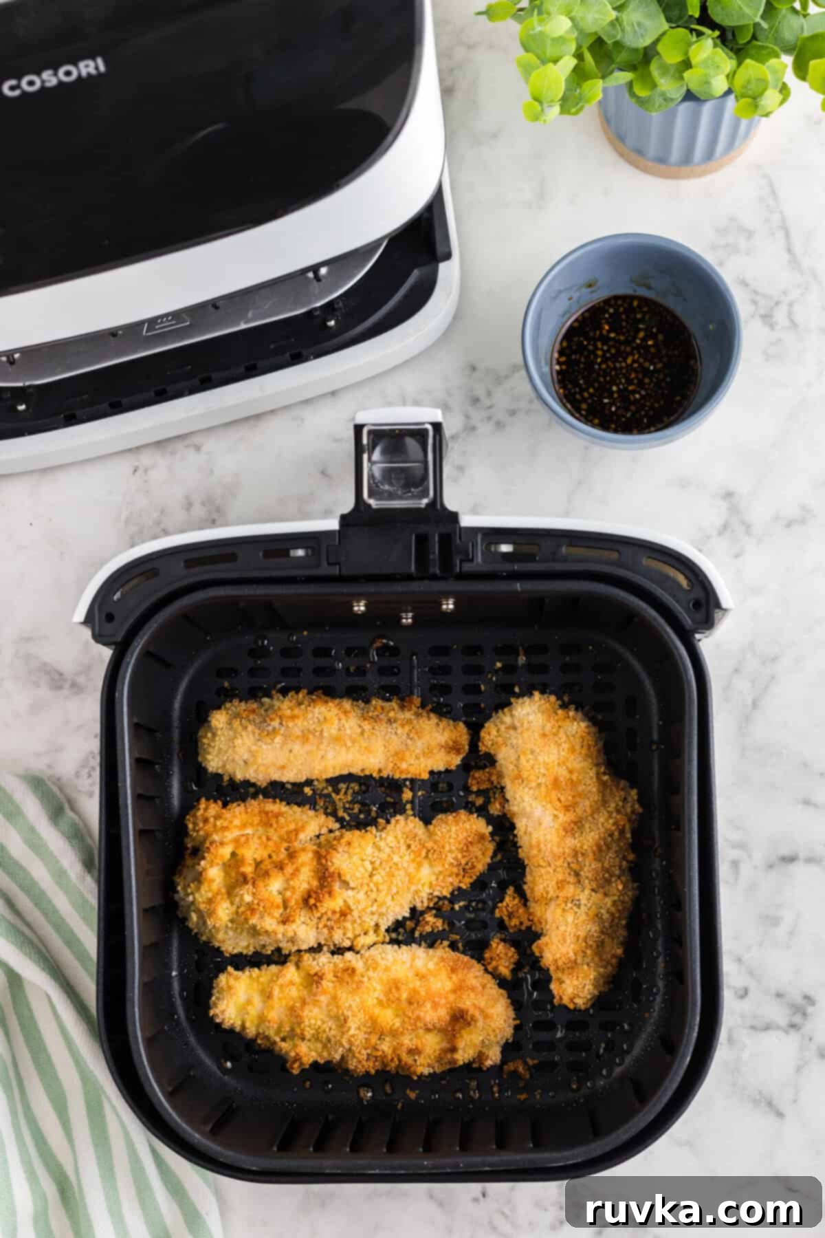 Crispy Air Fried Honey Garlic Chicken Strips 8 Golden brown, cooked chicken tenders in an air fryer basket.